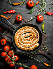 Fried sausage in a pan with garlic, tomatoes and herbs.
