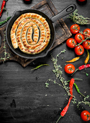 Fried sausage in a pan with garlic, tomatoes and herbs.