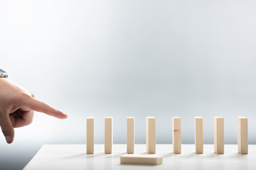 cropped view of man pointing with finger at wooden block row on white background