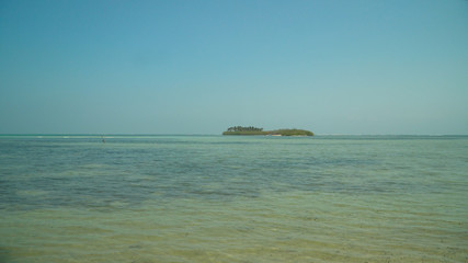 Tropical island with white sandy beach, palm trees in blue lagoon. Tanduyong island with turquoise water. Seascape, ocean and beautiful beach. Philippines, Anda, Pangasinan. Travel concept.