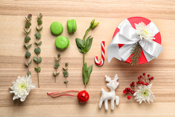 Flat lay composition with gift box, flowers and Christmas decor on wooden background