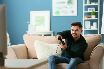 Young man playing video game at home