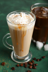 Glass cup of tasty coffee drink on color table