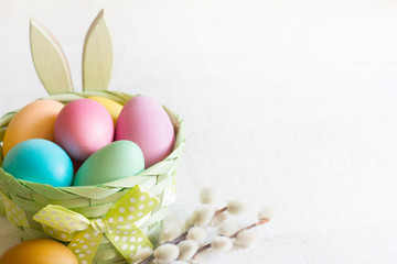 Easter simple colorfgul eggs in the basket and bunny on white wooden background