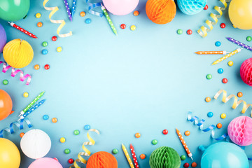 Birthday party background on blue. Top view. Frame made of colorful serpentine, balloons, candles and candies.