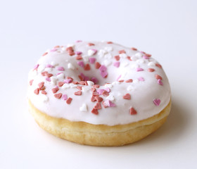White donut with sprinkles on a white wooden table. Retro style. Concept of breakfast Food detail. Close up. Pastel color.