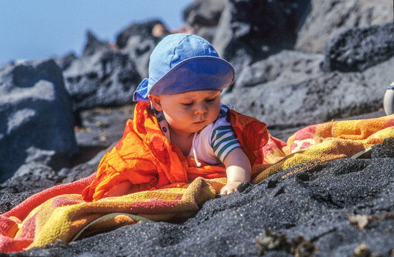 Cute Young Baby Enjoys Exploring The Black Sand At The Beach