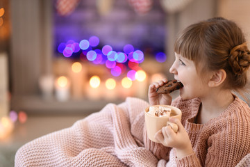 Cute little girl drinking hot chocolate and eating cookies at home on Christmas eve