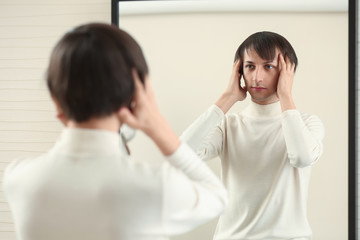 Obraz premium Young transgender man looking on his reflection in mirror