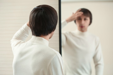 Obraz premium Young transgender man looking on his reflection in mirror