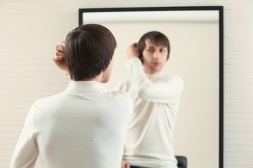 Fototapeta na wymiar Young transgender man looking on his reflection in mirror