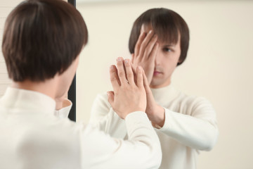 Displeased transgender man looking on his reflection in mirror