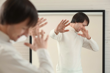 Displeased transgender man rejecting his reflection in mirror