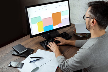 A man, a man sitting at a table in the office, working on a computer. The concept of office work. Copy space.