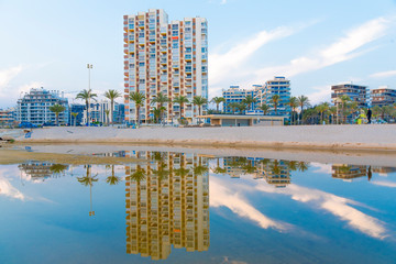 Reflexiones sobre el agua al atardecer. En una playa a al caer el dia sobre edificios de verano en...