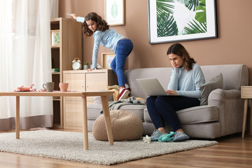 Busy mother with naughty daughter working at home