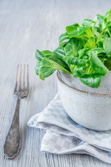 Frischer Feldsalat mit einer Gabel auf einem hellen Holzuntergrund