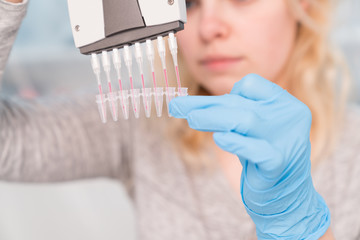 Young attractive woman work with PCR dispenser in  the laboratory of genetics