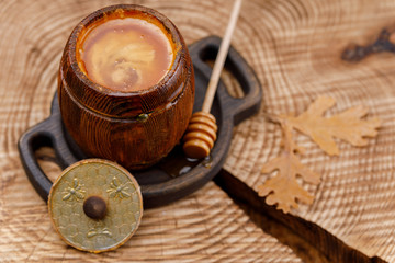 Open keg with honey on a wooden saw.