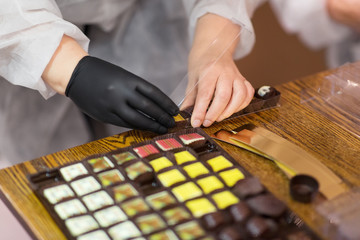 Fototapeta na wymiar sweets production and industry concept - confectioner or worker packing candies at confectionery shop