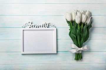 A bouquet of white tulips with a frame for inscription on blue boards