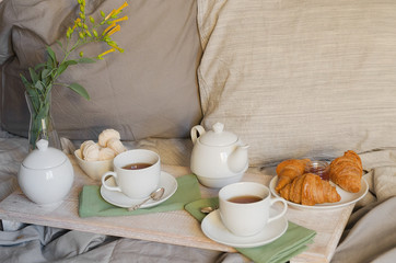 Relax breakfast  in bed. Teapot and two cups, croissants and meringue on the tray with flowers. Scandinavian style.