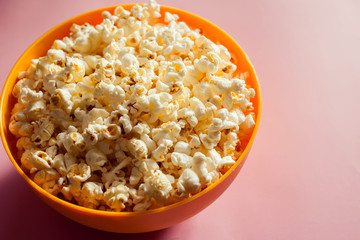 An orange bowl with popcorn isolated on pink background