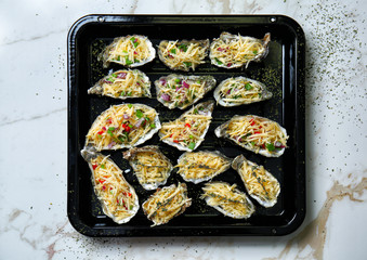 Baking sheet with tasty oysters, cheese and vegetables on light table