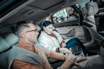 Fototapeta premium Husband wearing orange turtle neck choosing car for his wife