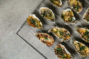 Cooling rack with tasty baked oysters on grey background