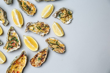 Tasty baked oysters with lemon on grey background