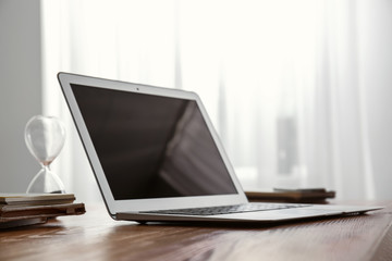 Modern laptop on wooden table in room