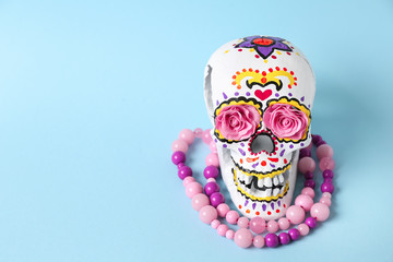 Painted human skull with beads for Mexico's Day of the Dead on color background