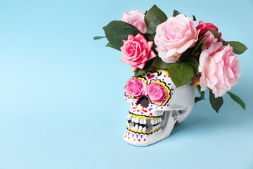 Painted human skull with flowers for Mexico's Day of the Dead on color background