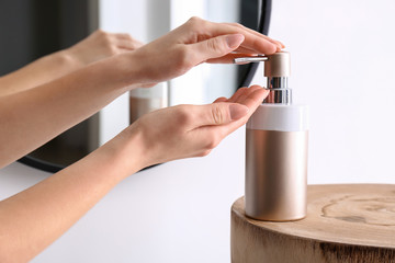Woman washing hands with liquid soap in bathroom