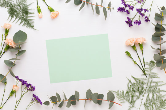 Fototapeta Flowers composition. Paper blank, carnation flowers, eucalyptus branches on pastel  background. Flat lay, top view, copy spaceFlat lay stiil life.