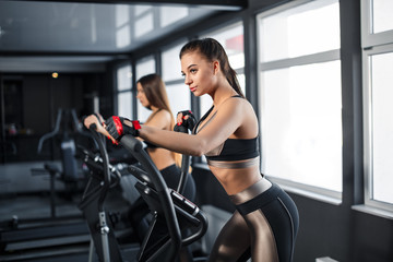 Fototapeta na wymiar Attractive young sports woman is working out in gym. Doing cardio training on treadmill. Running on treadmill