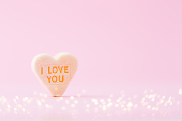 Pastel colored candy hearts in a bokeh background.