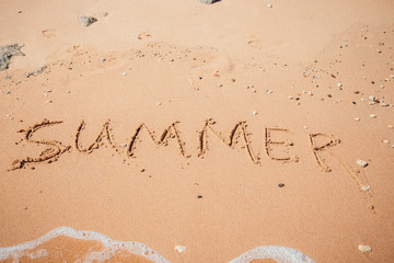 Inscription on wet sand Summer. Concept photo of summer vacation.