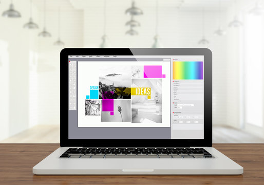laptop graphic design software on wooden desktop