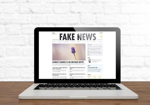 laptop fake news website on wooden desktop
