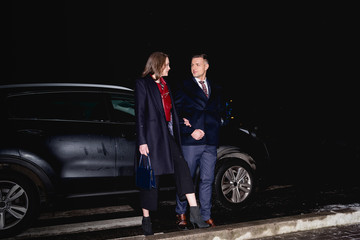 couple holding hands and looking at each other with car on background