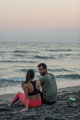 Fototapeta premium Sportswoman and sportsman Resting on Sandy Beach