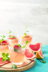 Pink alcoholic cocktail with grapefruit, ice and mint