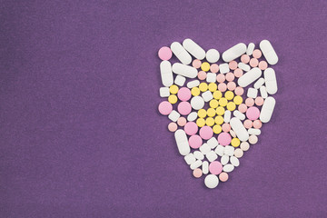 Heart shape made from colorful pills on white background. Concept