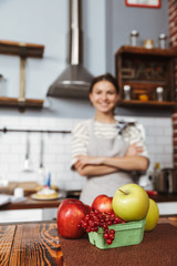 Happy young woman standing at the kitchen at home