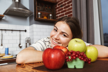 Happy young woman standing at the kitchen at home