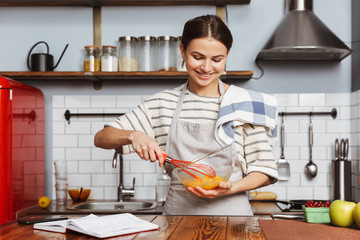 Happy young woman standing at the kitchen at home