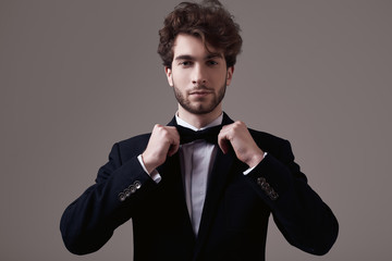 Handsome elegant man with curly hair wearing tuxedo