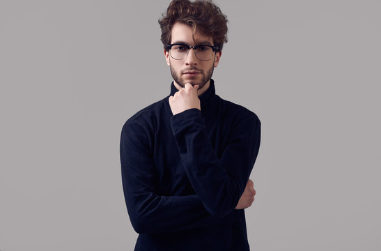 Handsome elegant man with curly hair wearing black turtleneck and glasses